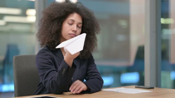 Pensive African Businesswoman Flying Paper Plane