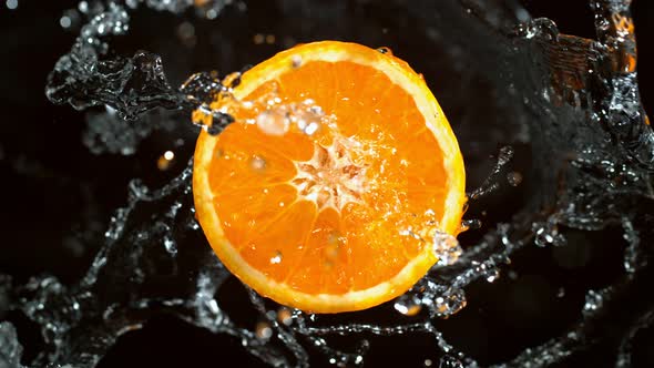Super Slow Motion Shot of Rotating Fresh Orange Slice and Splashing Water at 1000Fps
