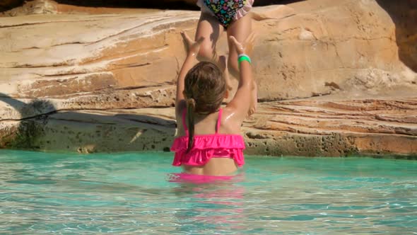 Two Sibling Girls are Jumping in the Swimming Pool