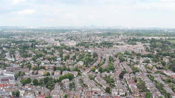 Dolly forward drone shot over dense residential buildings in West London city skyline in background