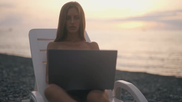 A Female Freelancer is Working on Laptop Near Sea