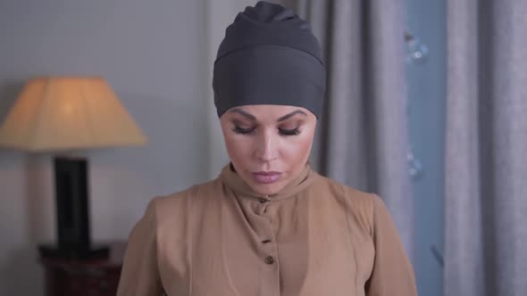 Portrait of Modern-looking Blond Woman Putting on Traditional Islamic Hijab