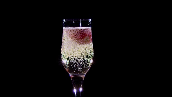 Slow Motion. Strawberry in Glass with Champagne Wine Covered Bubbles