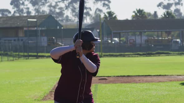 Mixed race female baseball player, hitter, swinging bat for pitched ball