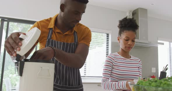 Video of happy african american couple cooking together in kitchen