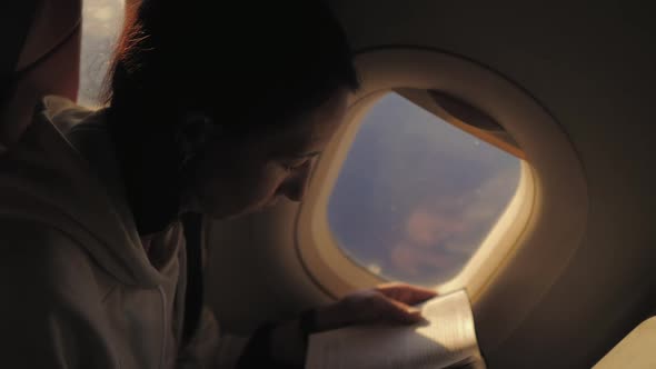 Woman Reading Book Inside Airplane