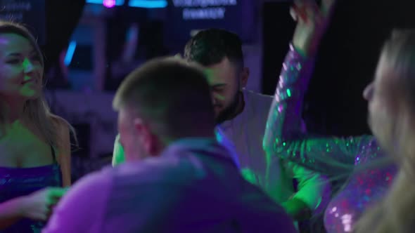 Happy Bearded Handsome Caucasian Man Dancing with Friends in Night Club Lights