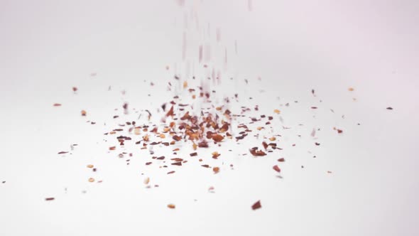 Chilli Flakes Falling On White Background - close up, slow motion