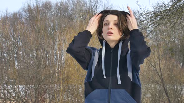 Early Spring Portrait of Young Athletic Girl Doing Exercise in the Morning in the Park Wearing Dark