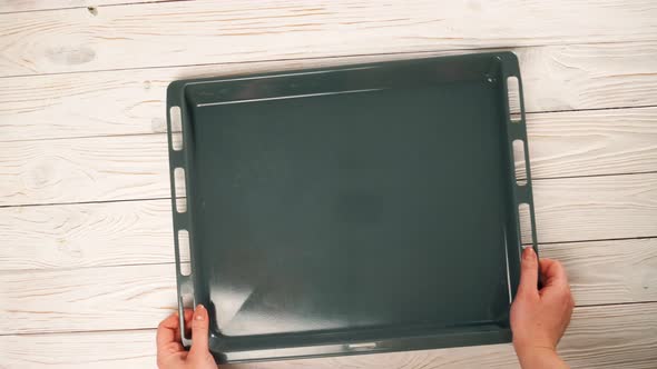 Woman Puts an Empty Baking Tray on the Table Owerhead View