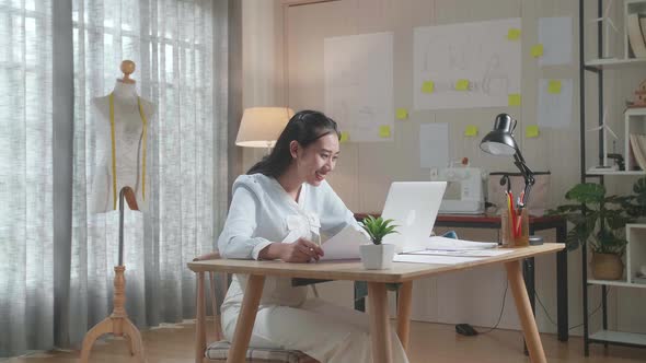 Asian Woman Designer Looking At The Layout Bond While Working With Laptop At The Office