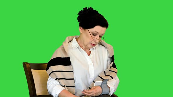 Senior Woman Measuring Her Blood Pressure on a Green Screen Chroma Key