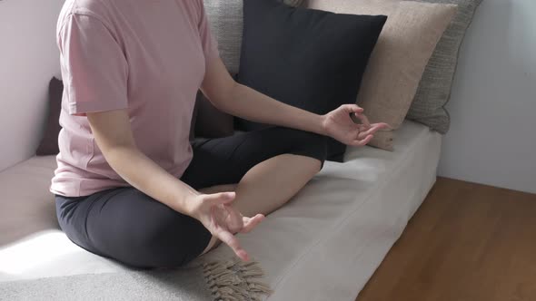 Unrecognizable woman sitting on couch, practicing yoga