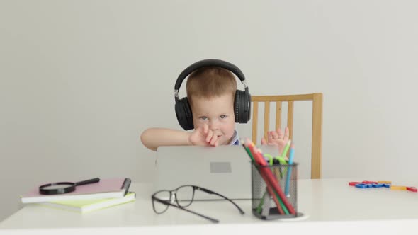 Funny Baby in Headphones Opening Laptop Cover at Table Starting Online Class alt