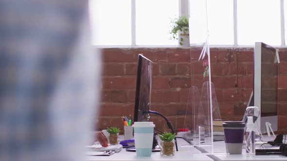 Mixed race businesswoman typing sitting in front of computer wearing face mask