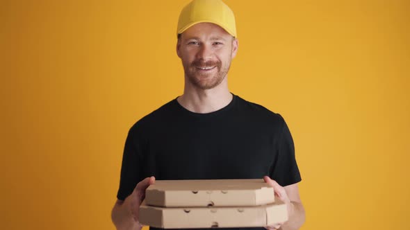 Positive deliveryman giving pizza to the camera