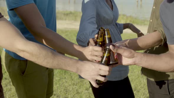 Cropped Shot of Friends Clinking Beer Bottles and Dancing