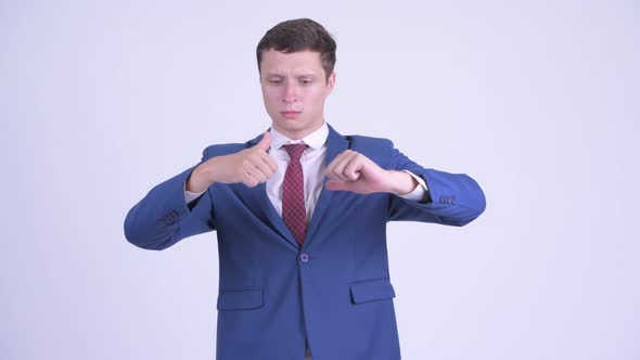 Confused Young Businessman Choosing Between Thumbs Up and Thumbs Down