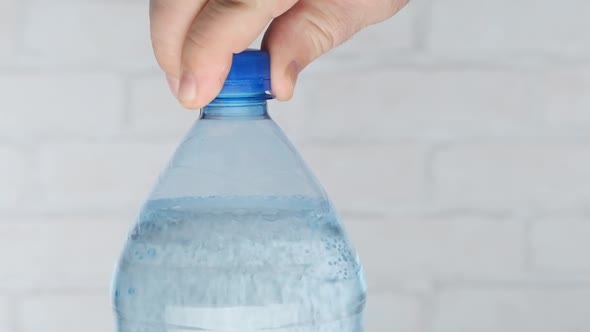 Male hand opens sparkling water in plastic bottle 