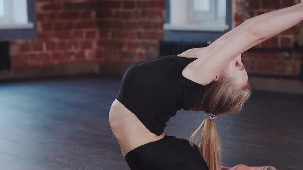 Gymnastics Blonde Young Woman Sitting in the Frog Pose and Bending Her Back Backwards Looking in the