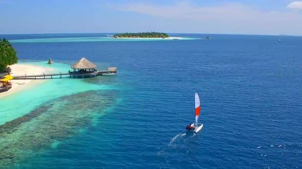 Aerial drone view of a man and woman sailing on a boat to a tropical island