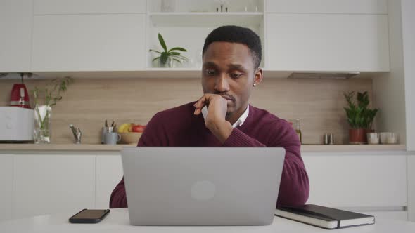 Young Black Man Can't Find a Comfortable Pose While Working From Home on a Laptop