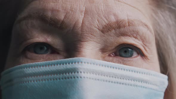 Close Up on the Blue Eyes of Old Gray Haired Woman with Face Mask