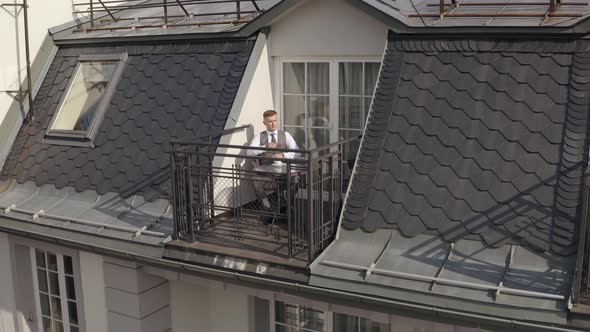 Man Groom Businessman Is Drinking Coffee From a White Cup on the Balcony at Home in Wedding Morning