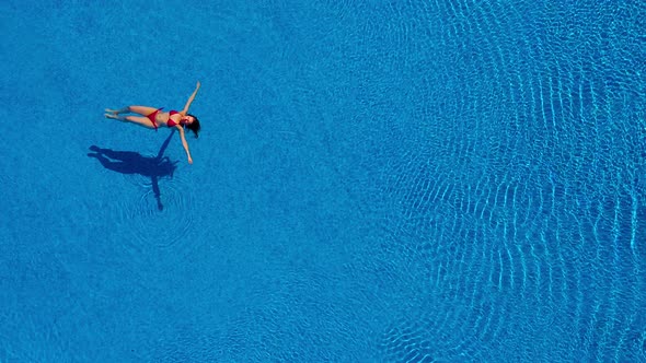 View From the Top As a Woman in a Red Swimsuit Swims Backstroke in the Pool