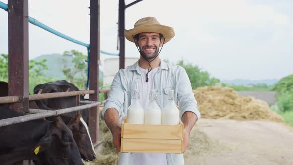 Portrait of Caucasian male dairy farmer hold bottle of milk in cowshed.