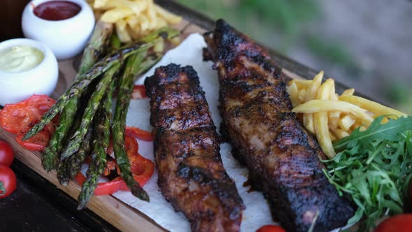 Delicious Beef or Pork Grilled Ribs Served with Aspargus and French Fries on a Wooden Board