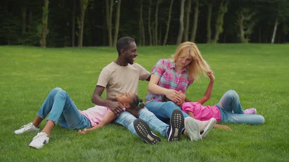 Multiracial Family with Daughters Resting in Park