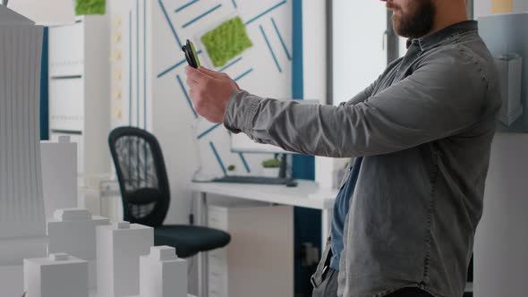 Close Up of Architect Using Digital Tablet and Building Model to Work on Construction Design