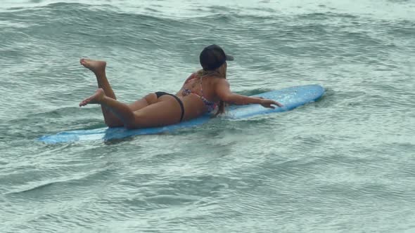 A young woman surfing in a bikini on a longboard surfboard.