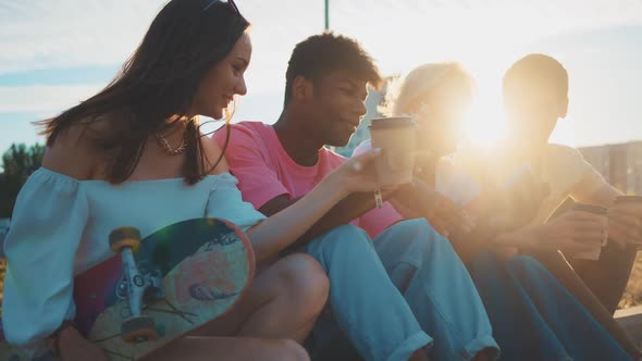 Happy Smiling Teenage Friends Laughing Outside at Something in Smartphone or Mobile Phone