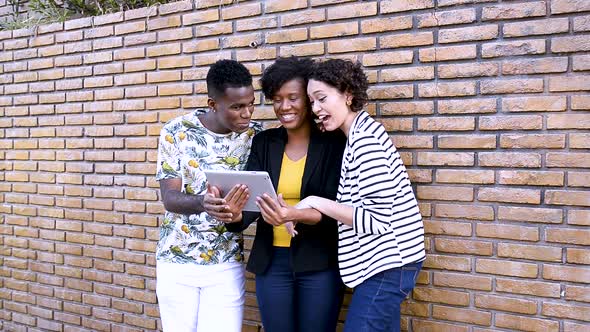 Three young people interact on video call on tablet outdoors