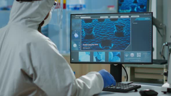 Back View of Chemist Man in Coverall Typing on Computer Analysing Vaccine Evolution