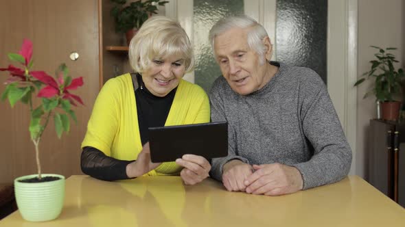 Pretty Mature Senior Couple Grandparents Making Video Call with Tablet at Home