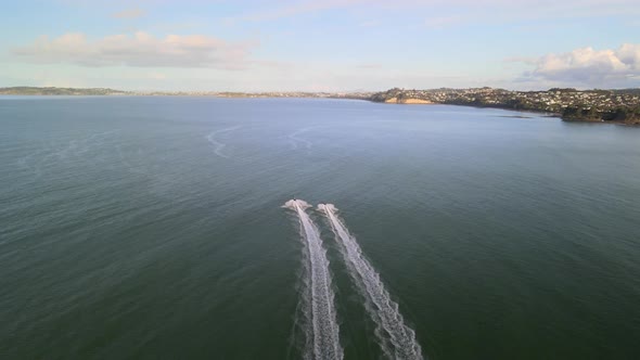 Flying quickly behind 2 jet skis along the coast of Orewa beach in New Zealand at sunset