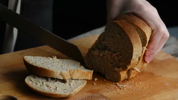 A Woman Cutting a Loaf of Bread with a Bread Knife. Slow Motion