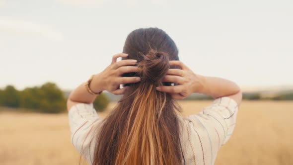 Girl Fixing Her Bun And Flaunting Her Long Brown Ombre Hair While Looking In Nature. - close up shot