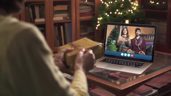 Online Christmas, family opening present on internet video call with laptop