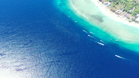 Deep blue sea bordering azure lagoon with calm clear water where many boats sailing around white bea