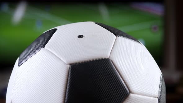 A Soccer Ball Spinning Against the Background of a TV with a Football Match