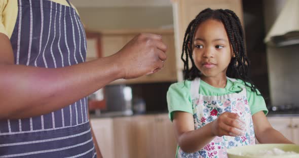 Happy african american father and daughter baking together, playing with flour in kitchen