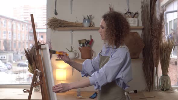 Professional Artist Woman Paints a Picture in the Workshop