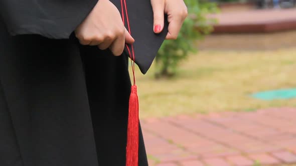 Woman in Academic Dress Holding Graduation Cap With Red Tassel, Ceremony