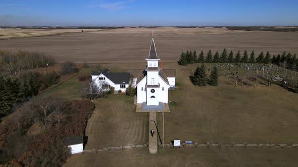 Aerial footage in 4k of rural countryside church in Alberta, Canada. Person walking along path leadi