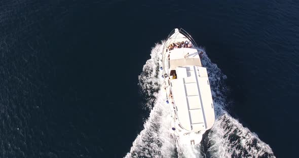 White Motor Boat with Tourists at the Stern Floats on the Sea