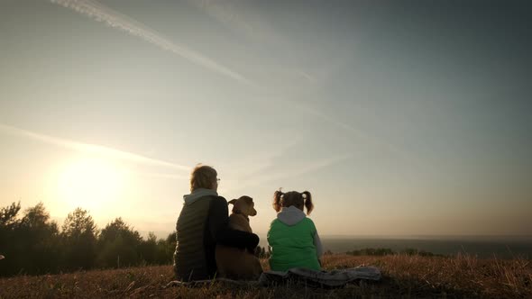 Silhouettes of Woman with Little Daughter and Pet Dog Sitting During Amazing Sunset